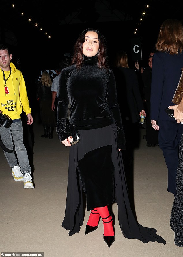 The Married At First star wore a black velvet turtleneck and a mixed fabric midi skirt with flowing side detailing.  She opted for a pair of bright red tights and pointed strappy heels