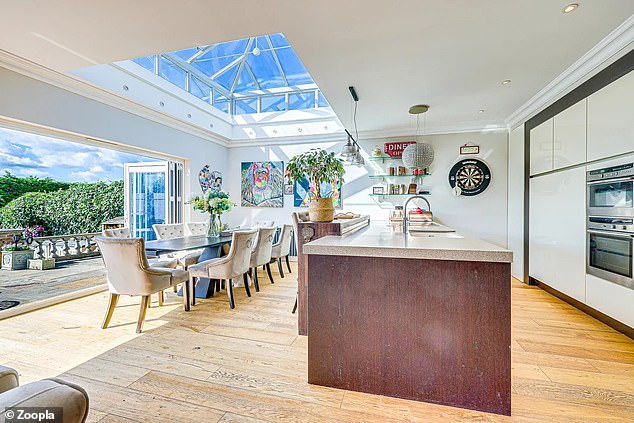 The large open living room houses a modern kitchen with cooking island and dining area