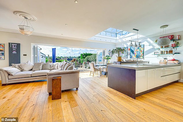 The living room has oak floors and double doors that extend over one wall and overlook the garden