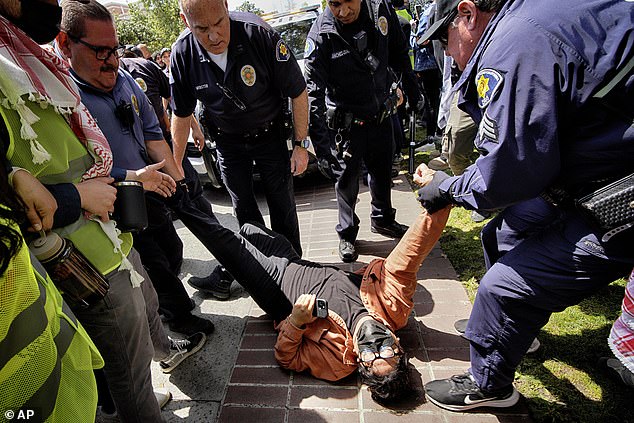 A University of Southern California protester is detained by USC Department of Public Safety officers during a pro-Palestinian occupation on campus