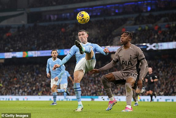 MANCHESTER, ENGLAND – DECEMBER 03: Phil Foden of Manchester City controls the ball for Destiny Udogie of Tottenham Hotspur during the Premier League match between Manchester City and Tottenham Hotspur at Etihad Stadium on December 3, 2023 in Manchester, England.  (Photo by James Gill - Danehouse/Getty Images)