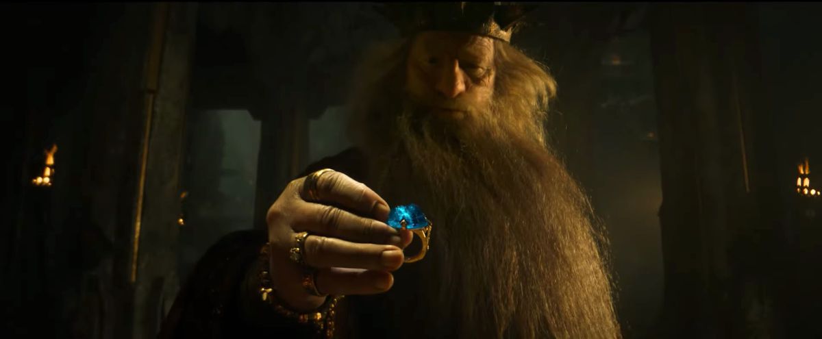 King Durin picks up a gold ring with a huge blue gemstone in it in The Lord of the Rings: The Rings of Power.