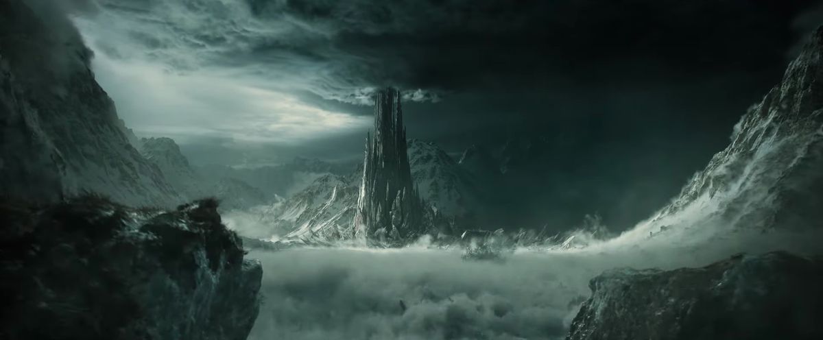 A black, jagged tower reaches up toward gray clouds at the bottom of a valley in the trailer for Season 2 of The Lord of the Rings: The Rings of Power