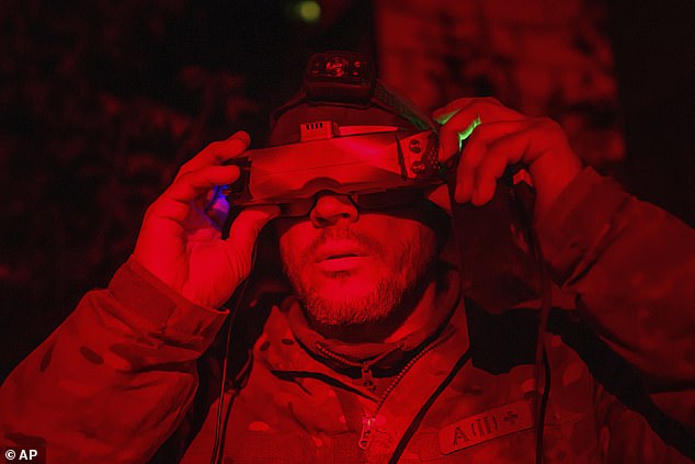 A Ukrainian soldier puts on headphones to control his FPV drone while on the front lines of the war