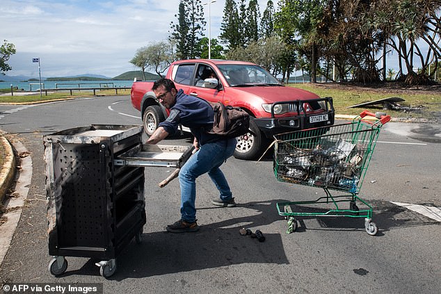 A local resident clears the roads of burned trash left by rioters