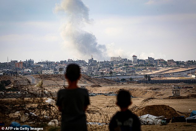 Boys see smoke rising during Israeli attacks east of Rafah on Monday.  The Biden administration is moving ahead with a $1 billion arms package to Israel despite the president's warnings not to attack the densely populated urban area