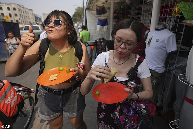 A customer gives a thumbs up while eating a taco straight from Rivera Martínez's grill.  The taco stand is the first to ever receive a Michelin star from the French food guide