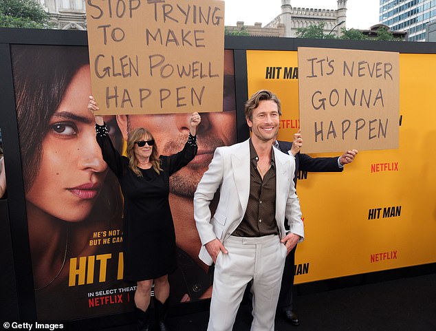 Powell's mother Cyndy – wearing a black dress – held up a sign that read: 'Stop Trying to Make Glen Powell Happen'