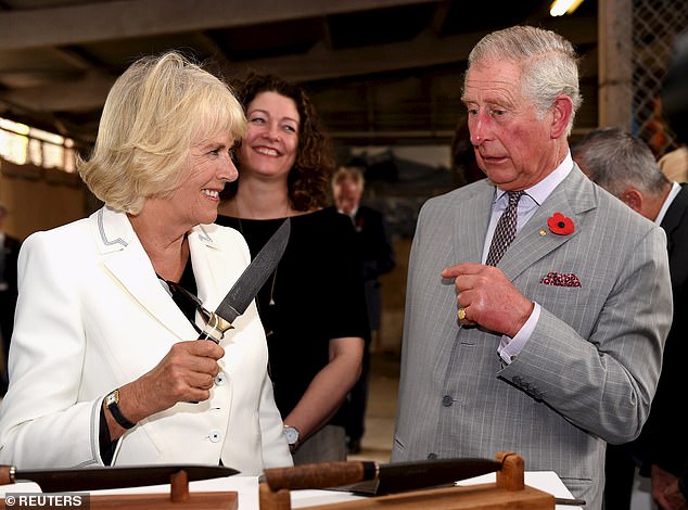 A grinning Camilla scares Charles by holding a large knife in the air during a visit to a winery in Australia