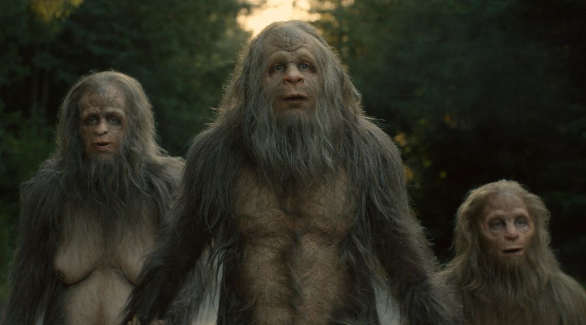 Three sasquatch creatures stare in surprise at something off-screen.
