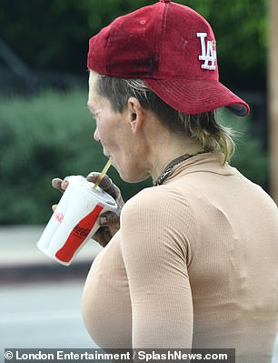 The ex-model wore a nude top, brown pants, brown Converse and a red baseball cap