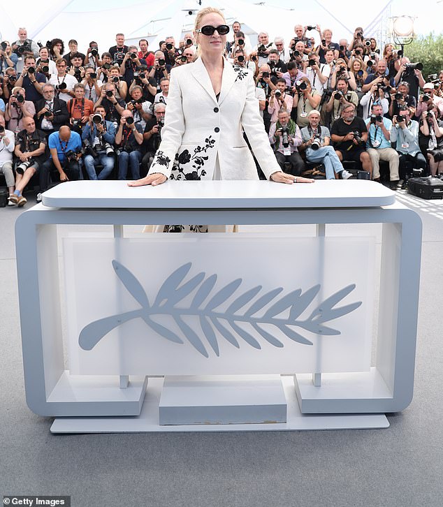 The stage had the Cannes magazine symbol at the front and a wall of photographers behind Uma