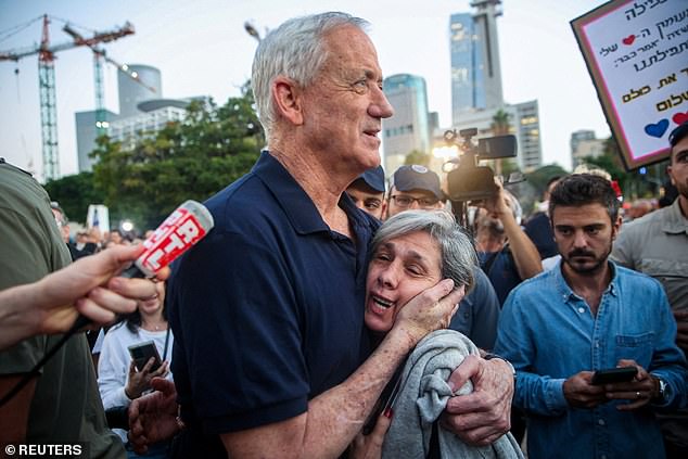 Gantz hugs a woman as he walks toward the hostages' relatives.  Gantz said: 'If you choose the path of fanatics and lead the entire nation to the abyss, we will be forced to leave the government'