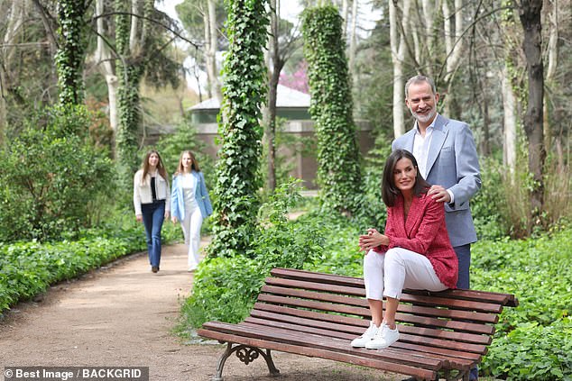 In a more artsy pose, Letizia sits down on a bench with her husband behind her, while the couple's daughters can be seen in the distance