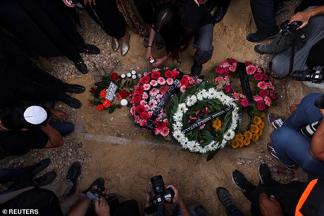 Mourners gather at the grave of German-Israeli Shani and lay flowers on the ground