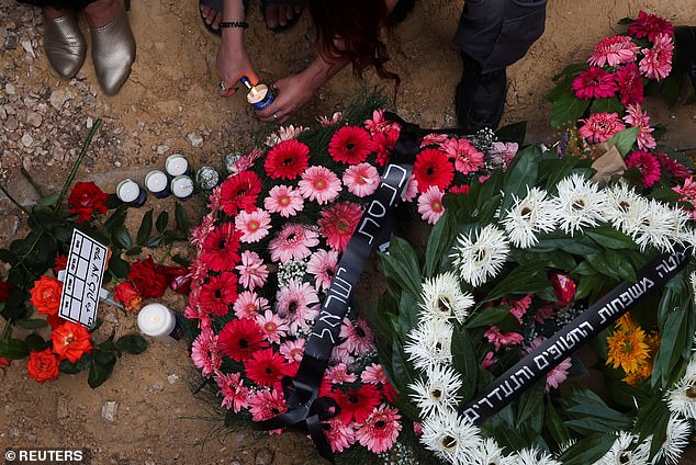 A mourner lights a candle at Shani's grave yesterday, laden with floral tributes