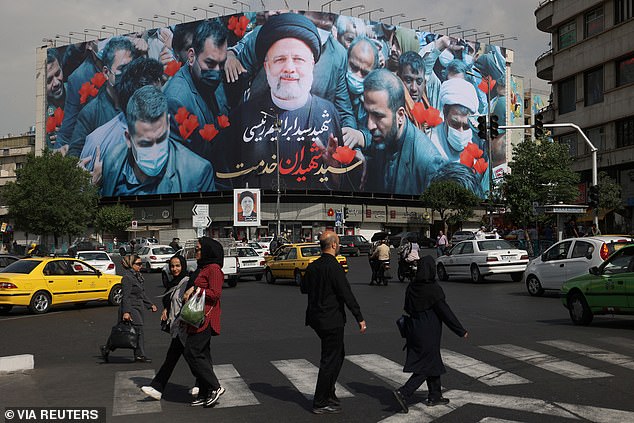 People walk past a billboard with a photo of the late Iranian President Ebrahim Raisi on a street in Tehran, Iran, May 21, 2024