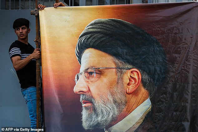 Men hang a huge portrait of the late Iranian President Ebrahim Raisi outside the Iranian embassy in Baghdad on May 20, 2024