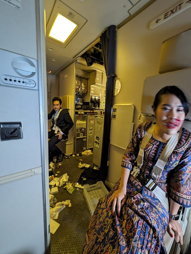 A passenger on board a Singapore Airlines plane from Britain has described the extreme turbulence that killed a fellow pilot in a tragic incident today.  Pictured: Crew are seen in the aftermath of extreme turbulence on the Singapore Airlines plane today