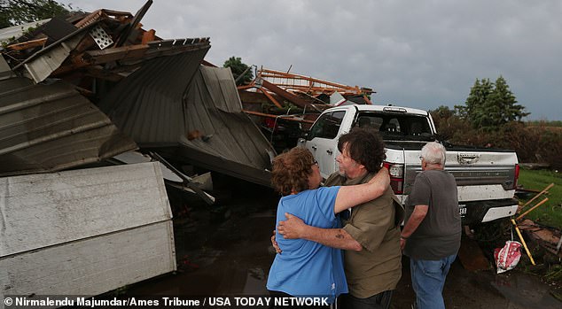 Iowa resident June Handsaker comforts her brother Larry after a tornado destroyed his home in Nevada, Iowa, Tuesday afternoon