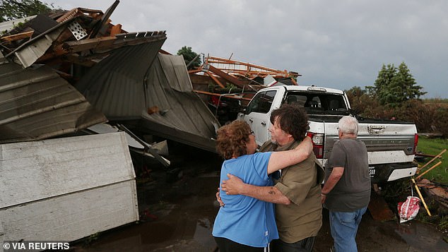 June Handsaker comforts his brother Larry Handsaker after a tornado damages his home in Nevada, Iowa