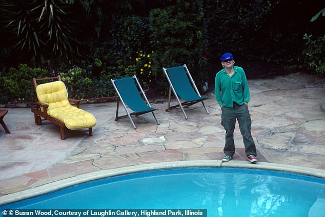 Painter David Hockney seen posing next to his pool in 1980 wearing jeans, a green button-down and mismatched sneakers