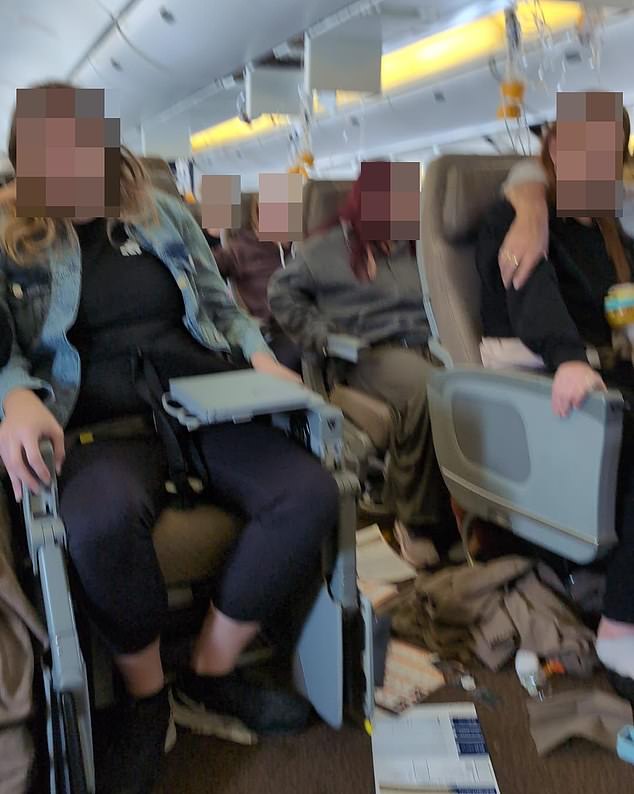 Passengers are seen in the cabin after the incident, with belongings scattered on the floor and oxygen masks dangling from above