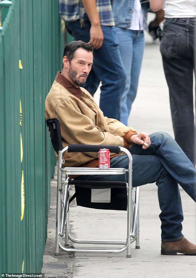 Reeves sat cross-legged on a folding chair with a lit cigarette in hand and a can of refreshing drink placed next to him