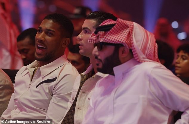 Joshua, who sat ringside next to Cristiano Ronaldo (center), spoke to Eddie Hearn immediately after the fight