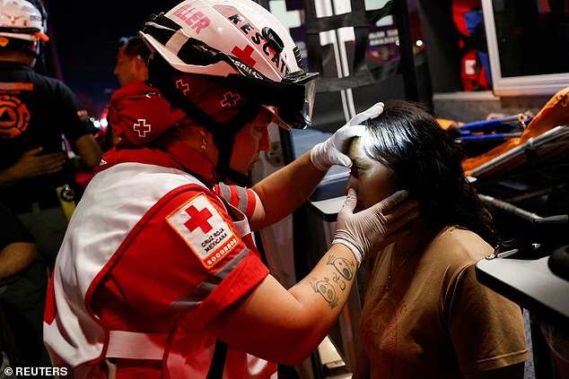 A Mexican Red Cross rescuer checks on a girl at the site after a gust of wind caused a structure to collapse during a campaign rally