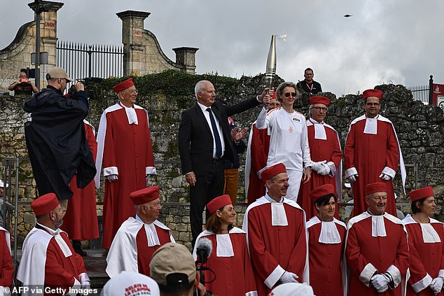 Mayor of Saint-Emilion Bernard Lauret holds the Olympic torch as part of the Olympic and Paralympic torch relay, ahead of the Paris 2024 Olympic and Paralympic Games, in Saint-Emilion, south-west France on Thursday