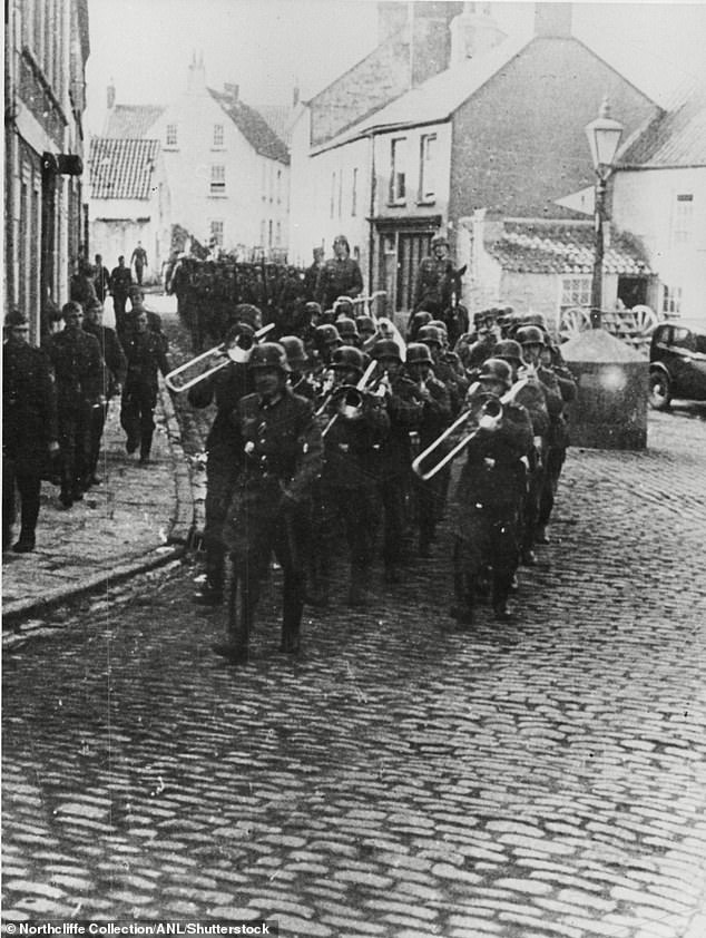 Captives consisting of Jews, POWs and some Roma, who were transported to Alderney to build fortifications as part of the German war effort.  Pictured: German troops march down the main street of Alderney during the occupation