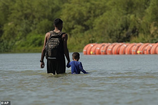 A migrant with a child crosses the Rio Grande River from Mexico to Texas