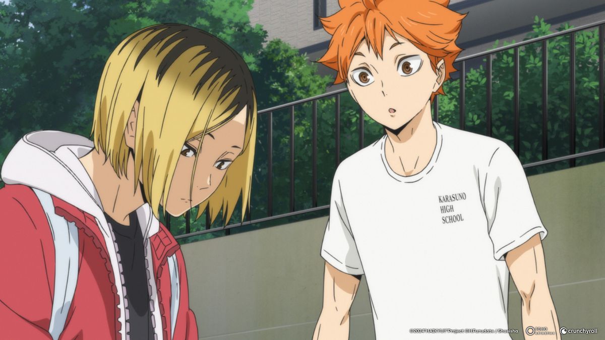 A blond boy in a red tracksuit sits down, while an orange-haired boy in a white T-shirt looks at him curiously