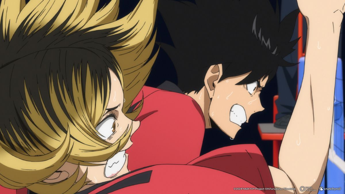 A blond boy and a dark-haired boy growl as they play intense volleyball.  Both wear red shirts.