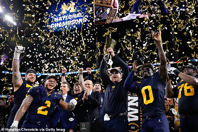 Michigan Wolverines head coach Jim Harbaugh raises the championship trophy