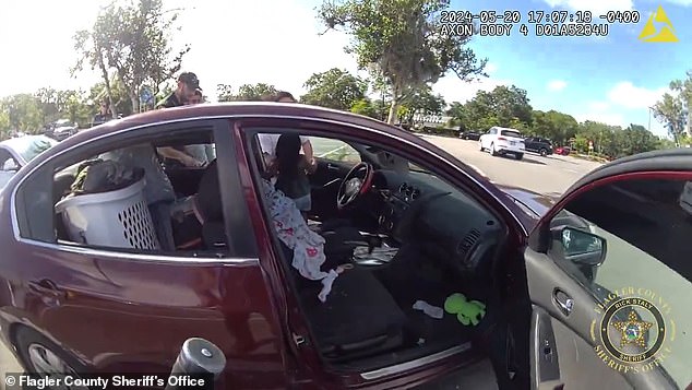 The two adults found outside the car when officers arrived said the child had been in the Nissan Altima for 10 minutes.  (photo: the little girl is removed from the driver's seat)