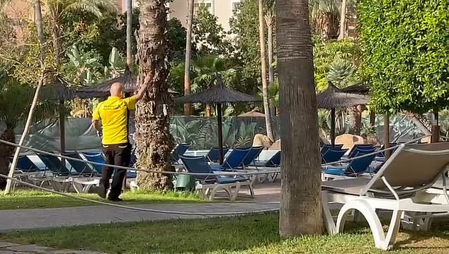 A security guard in a bright yellow top keeps an eye out for sun worshipers trying to cheat the system by going to bed early