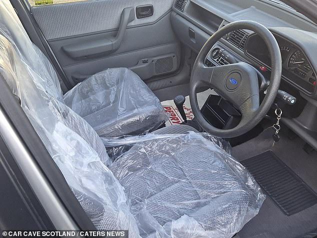 The interior looks unused, the seat covers are still on to protect the fabric seats