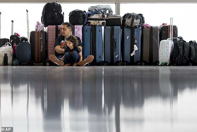 Samuel Tadros and his daughter Serenity 3 sit with the family's suitcases after their flight to New York was canceled at Nashville International Airport on Thursday, May 23, 2024