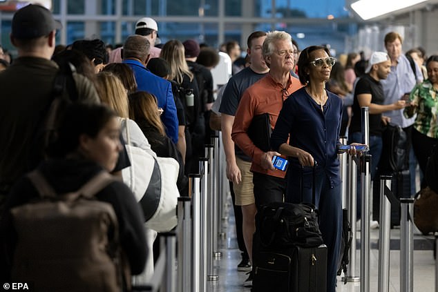 Travelers wait in line to go through the Transportation Security Administration (TSA) security checkpoint at Ronald Reagan Washington National Airport in Arlington, Virginia