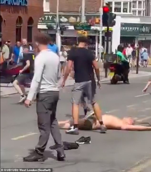 One shirtless supporter was left sprawled on the road after a fight with a rival fan