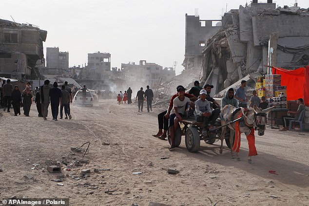 Displaced Palestinians walk through a destroyed street in Khan Yunis in the southern Gaza Strip on May 24, 2024