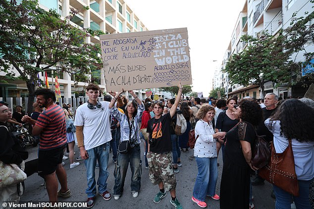 Protesters in Ibiza hold up posters during a demonstration against tourism on Friday, including one that reads 'My lawyer lives in a rented car'