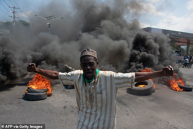 A protester reacts as tires burn in the street during a demonstration following the resignation of Prime Minister Ariel Henry, in Port-au-Prince, Haiti, on March 12, 2024