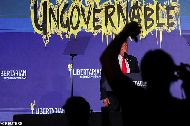 An attendee at the Libertarian National Convention gives a thumbs down as former President Donald Trump speaks at the Washington Hilton on Saturday evening