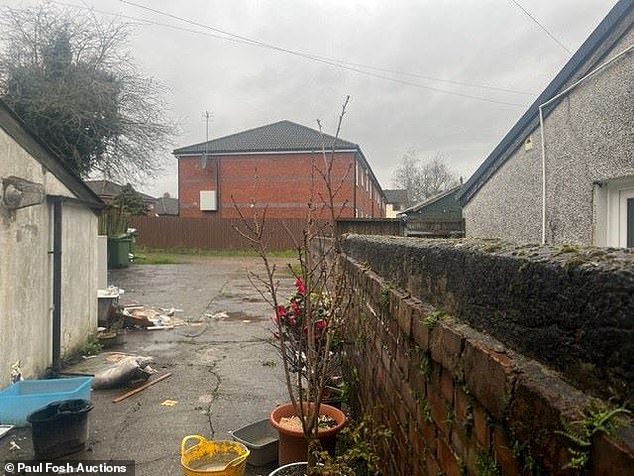 A mop bucket, empty plant pots and plastic boxes line the side entrance to the car park behind the takeaway