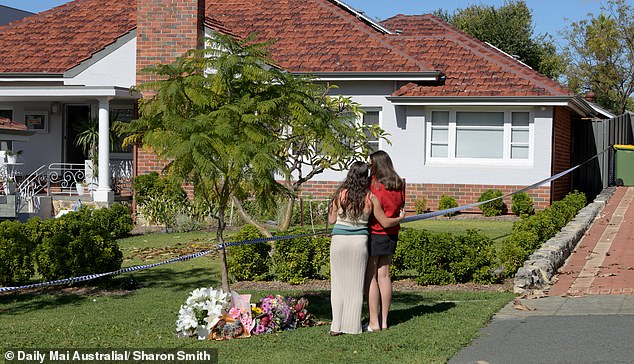 In the photo, two young women leave floral tributes at Peteczyc's home on Berkley Street