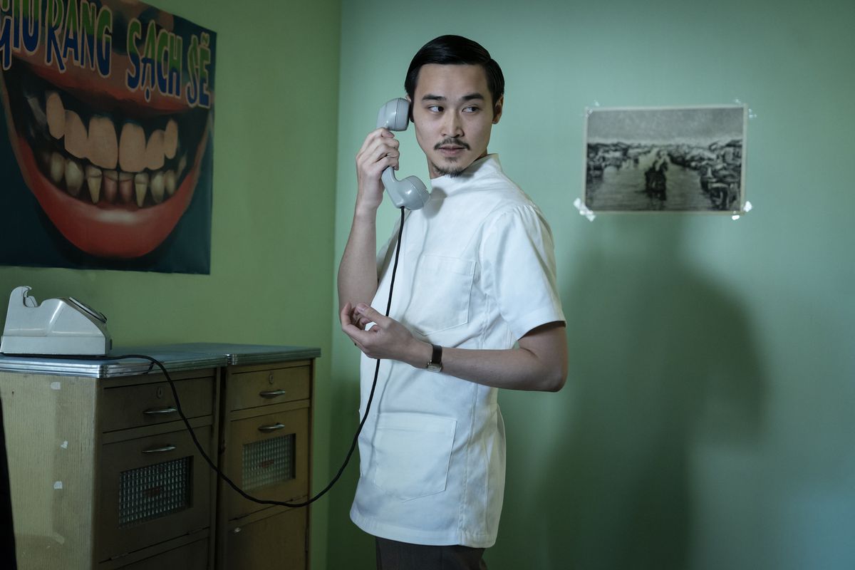 Mẫn (Duy Nguyễn) answers a phone and looks around in a still from The Sympathizer