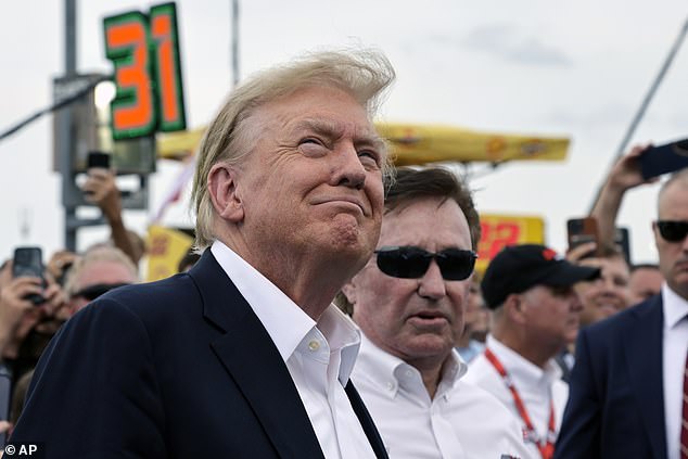 President Donald Trump smiles as a military plane performs a flyover while attending the NASCAR Coca-Cola 600